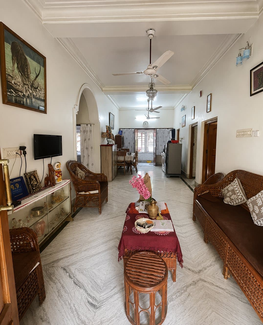 The living and dining room of an owner-run homestay, with cane furniture and a marble floor